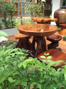 a wooden table and stool in a garden at Kim Hotel At Morleng in Bangkok