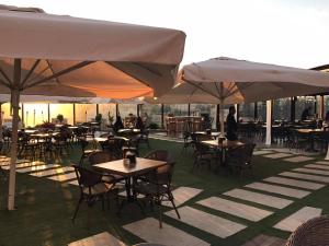 eine Außenterrasse mit Tischen, Stühlen und Sonnenschirmen in der Unterkunft Ankars Suites & Hotel in Ramallah