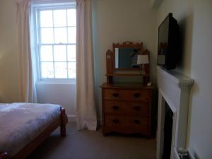 a bedroom with a bed and a mirror and a dresser at Elibank House Apartment in Walkerburn