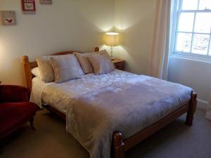 a bedroom with a large bed with pillows and a window at Elibank House Apartment in Walkerburn