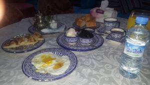 einen Tisch mit blauen und weißen Teller mit Speisen und einer Flasche Wasser in der Unterkunft Hôtel Tijani in Fès