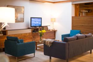 a living room with two chairs and a couch and a tv at Hotel Alcides in Ponta Delgada