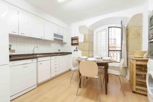 a kitchen with white cabinets and a table and chairs at The Rentals Collection | Loreak in San Sebastián