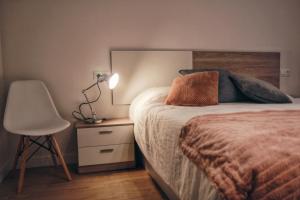 a bedroom with a bed and a chair and a lamp at Apartamento Erdi Kale in Azpeitia