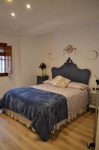 a bedroom with a large bed with a blue blanket at El Patio De La Aljama in Córdoba