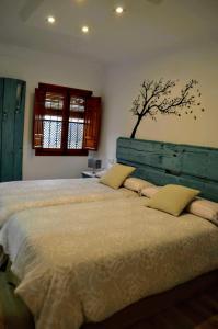 una camera da letto con un grande letto con un albero sul muro di El Patio De La Aljama a Cordoba