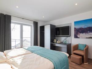 1 dormitorio con 1 cama, TV y silla en Amel Mitte en Amblève