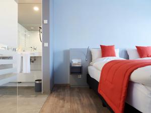 um quarto com uma cama com um cobertor vermelho e uma casa de banho em Amel Mitte Bed & Breakfast em Amblève