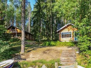 a log cabin in the woods with a boat in front of it at Holiday Home Salmensuu by Interhome in Havumäki