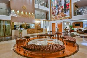 a lobby with a large couch and tables and chairs at Golden Lis Hotel Boutique in Goiânia
