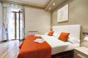 a bedroom with a large bed with an orange blanket at The Rentals Collection | Camelot in San Sebastián