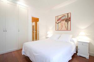 a white bedroom with a white bed and a picture on the wall at The Rentals Collection | Leonardo in San Sebasti&aacute;n