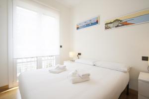 een witte slaapkamer met een groot wit bed met handdoeken erop bij The Rentals Collection | Avenida II in San Sebastian