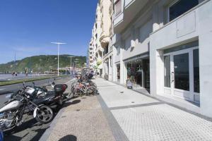 um grupo de motocicletas estacionadas num passeio ao lado de um edifício em The Rentals Collection | Gros Beach em San Sebastián