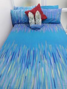 een bed met een blauw dekbed en 2 schoenen bij Standard Room with Balcony 1569 in Tagaytay