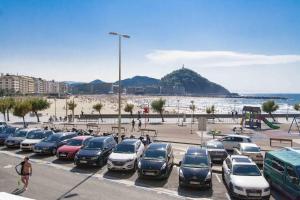 Un sacco di auto parcheggiate in un parcheggio sulla spiaggia. di The Rentals Collection | Scala a San Sebastián