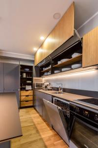 a kitchen with stainless steel appliances and wooden cabinets at Maironis 2 - Grand Apartment in the Heart of Kaunas in Kaunas