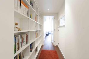 un pasillo con estanterías blancas llenas de libros en The Rentals Collection | Gros Beach, en San Sebastián
