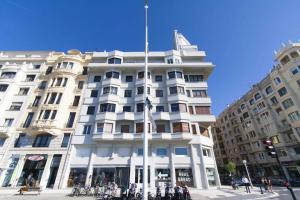 un gran edificio blanco con un poste de bandera delante de él en The Rentals Collection | Gros Beach, en San Sebastián