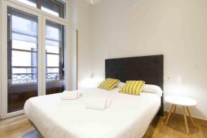sypialnia z dużym białym łóżkiem z żółtymi poduszkami w obiekcie The Rentals Collection | Dream w mieście San Sebastián