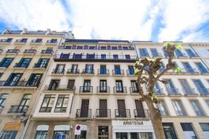 Un alto edificio bianco con un albero davanti di The Rentals Collection | Verona a San Sebastián