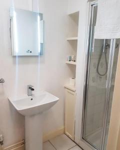 uma casa de banho branca com um lavatório e um chuveiro em Littledean House Hotel em Cinderford
