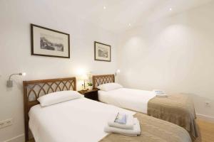 2 camas en una habitación con paredes blancas en The Rentals Collection | Gallery, en San Sebastián