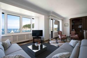 uma sala de estar com um sofá e uma televisão e janelas em The Rentals Collection | BellaVista em San Sebastián