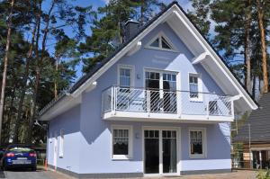 Cette maison bleue et blanche dispose d'un balcon. dans l'établissement Ferienhaus Müritzidyll / EG-Appartement, à Marienfelde