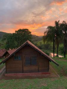 a small wooden house with a sunset in the background at Pousada Gota de Minas in Santo Antônio do Leite