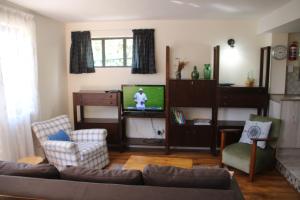 a living room with a couch and a tv at Fisherman's Watch Cottage in Cape Town