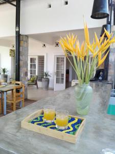a tray with two glasses of orange juice and a vase with flowers at Urban Lodge in Bujumbura