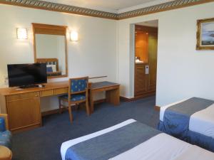 Cette chambre comprend un lit et un bureau avec une télévision. dans l'établissement Sea View Resort Hotel & Apartments, à Kuala Belait
