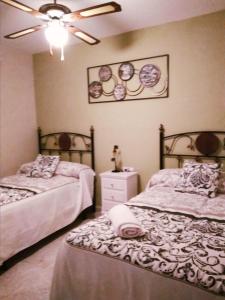 een slaapkamer met 2 bedden en een plafondventilator bij Apartamento Turistico La Victoria in Trujillo