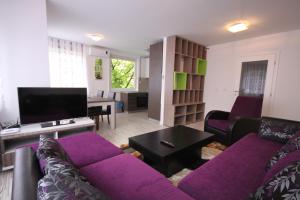 sala de estar con sofá púrpura y TV en Sarajevo Apartments, en Sarajevo