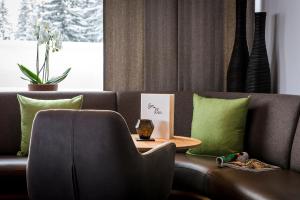 ein Wohnzimmer mit einem braunen Sofa und grünen Kissen in der Unterkunft Cresta.Alpin.Sport.Hotel in Lech am Arlberg