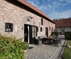 un edificio de ladrillo con un patio con mesa y sillas en B&B Goed Ten Hulle, en Pittem