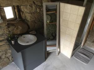 y baño de piedra con lavabo y ducha. en Casetta en Olivese
