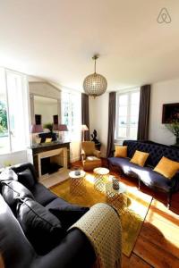 uma sala de estar com sofás de couro e uma lareira em Belle maison bourgeoise de charme dans un domaine viticole em Libourne