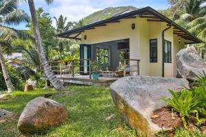 a house on the beach with rocks in front of it at Domaine Desaubin Luxury Villas in Takamaka
