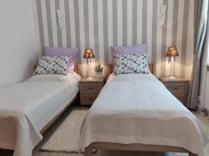 - 2 lits dans une chambre avec 2 lampes sur les tables de chevet dans l'établissement Apartament Helena, à Świnoujście