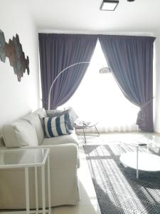 een woonkamer met een witte bank en paarse gordijnen bij Guesthouse at Shah Alam in Shah Alam