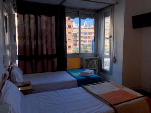 um quarto com 2 camas e uma grande janela em LÀtic Rooms em Alicante