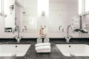 a bathroom with two sinks and two mirrors at Hotel Borg by Keahotels in Reykjavík