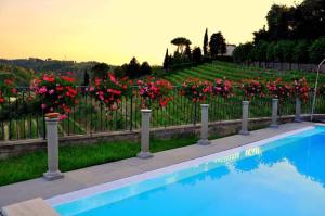 una valla con flores rosas y una piscina en RESIDENCE IL VIGNETO, en Lari