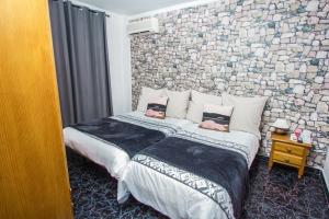 a bedroom with a large bed with a stone wall at Hostal Caminito del Rey in Alora