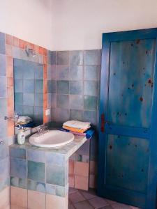 a bathroom with a sink and a blue door at Camisadu in Oliena