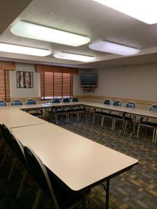 Sala de conferencias con mesas, sillas y TV en AmericInn by Wyndham Hampton en Hampton
