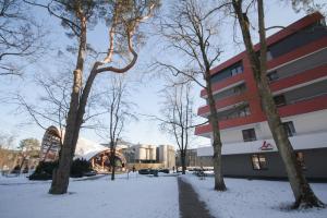 Un bâtiment dans la neige avec des arbres autour de lui dans l'établissement Akva Apartament 1, à Druskininkai