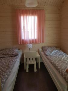 two beds in a room with a table and a window at Domki Siódme Niebo in Stegna